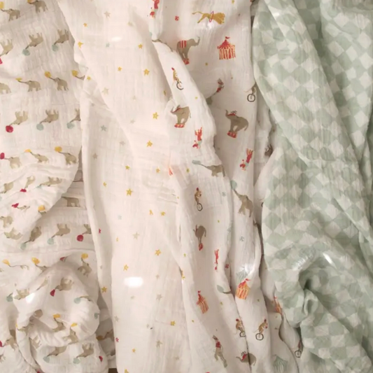 Stack of baby blankets with animal prints and a solid color. ADEN + ANAIS COTTON BABY SWADDLE 4 PACK - ELEPHANT CIRCUS