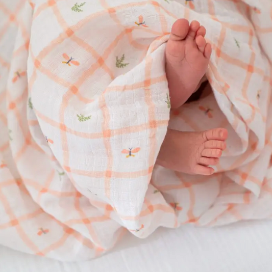 Baby feet peeking out from under a soft, patterned blanket. ADEN + ANAIS COTTON SWADDLE 4 PACK - COUNTRY FLORAL