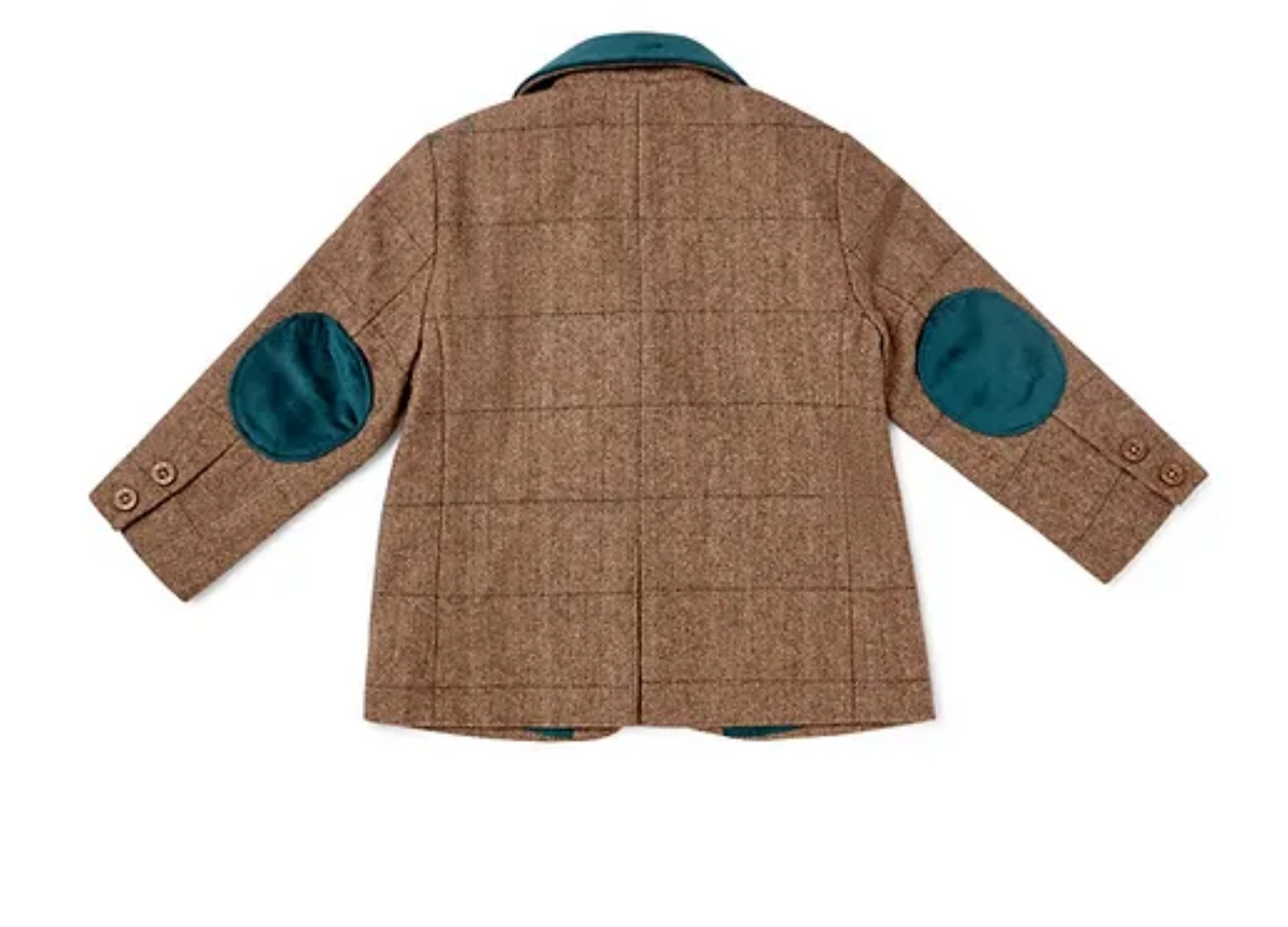 Eleanor Charles Boys Moloney Tweed Jacket in Teal Green trim colourway photographed flat lay from the back; warm caramel-brown herringbone tweed with subtle windowpane overcheck; peacock teal-blue velvet notched collar at the top; two large rounded oval peacock teal-blue velvet elbow patches on both sleeves at mid-sleeve, strongly contrasting against the caramel-brown tweed ground; two small Eleanor Charles horn cuff buttons per sleeve; centre back vent; peacock teal-blue lining faintly visible at the back