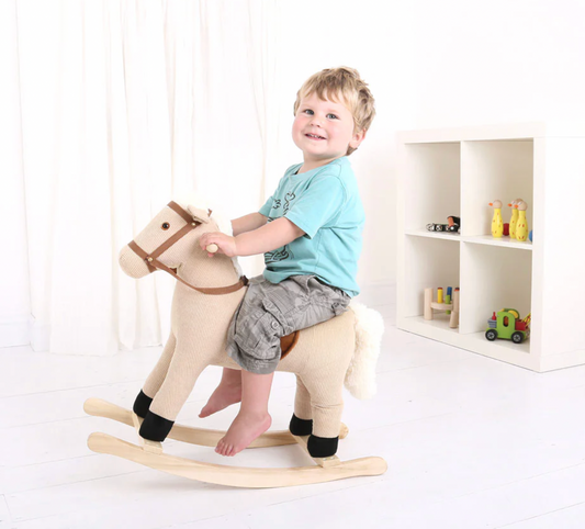 Child riding a rocking horse in a room with shelves and toys. CHILDREN'S CLASSIC RIDE ON ROCKING HORSE | BIGJIGS