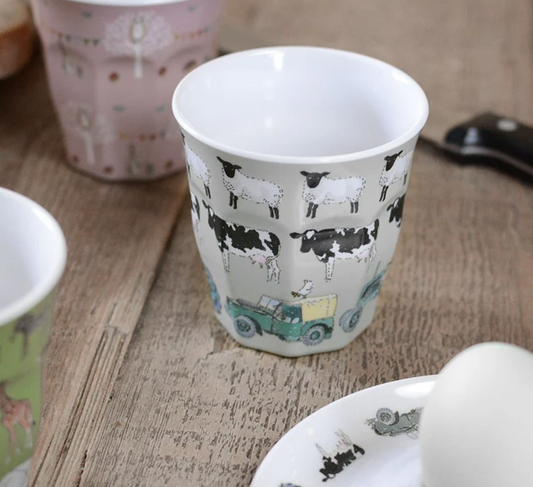Ceramic cup with farm animal design on a wooden surface. CHILDREN'S MELAMINE BEAKER - ON THE FARM | SOPHIE ALLPORT