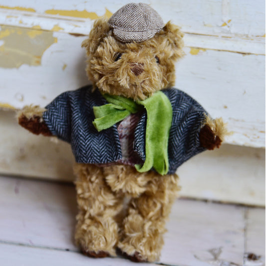 Teddy bear wearing a sweater and hat on a wooden surface. MINI DETECTIVE TEDDY IN TWEED WITH SCARF | POWELL CRAFT
