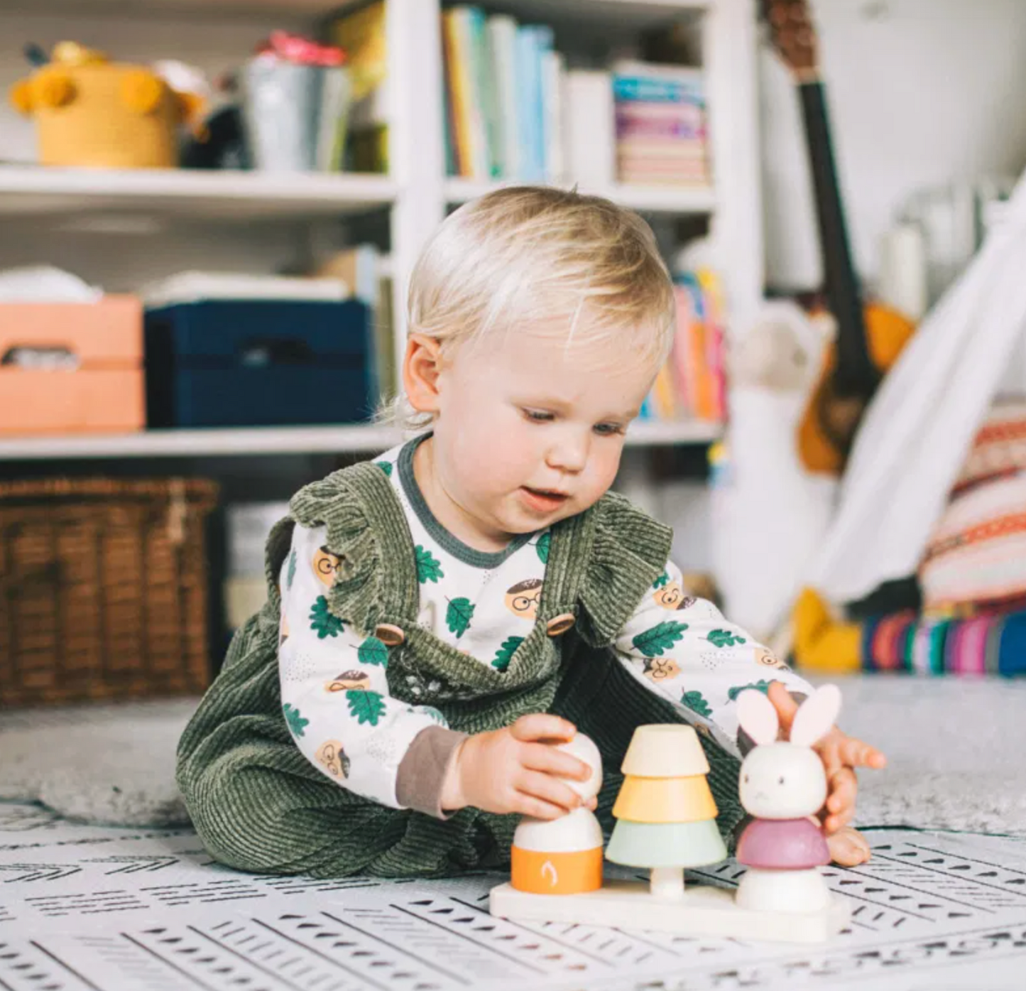 Child playing with wooden toys on a rug in a cozy room. MINI WOODEN NOUGHTS & CROSSES - TRAVEL SIZE | BIGJIGS