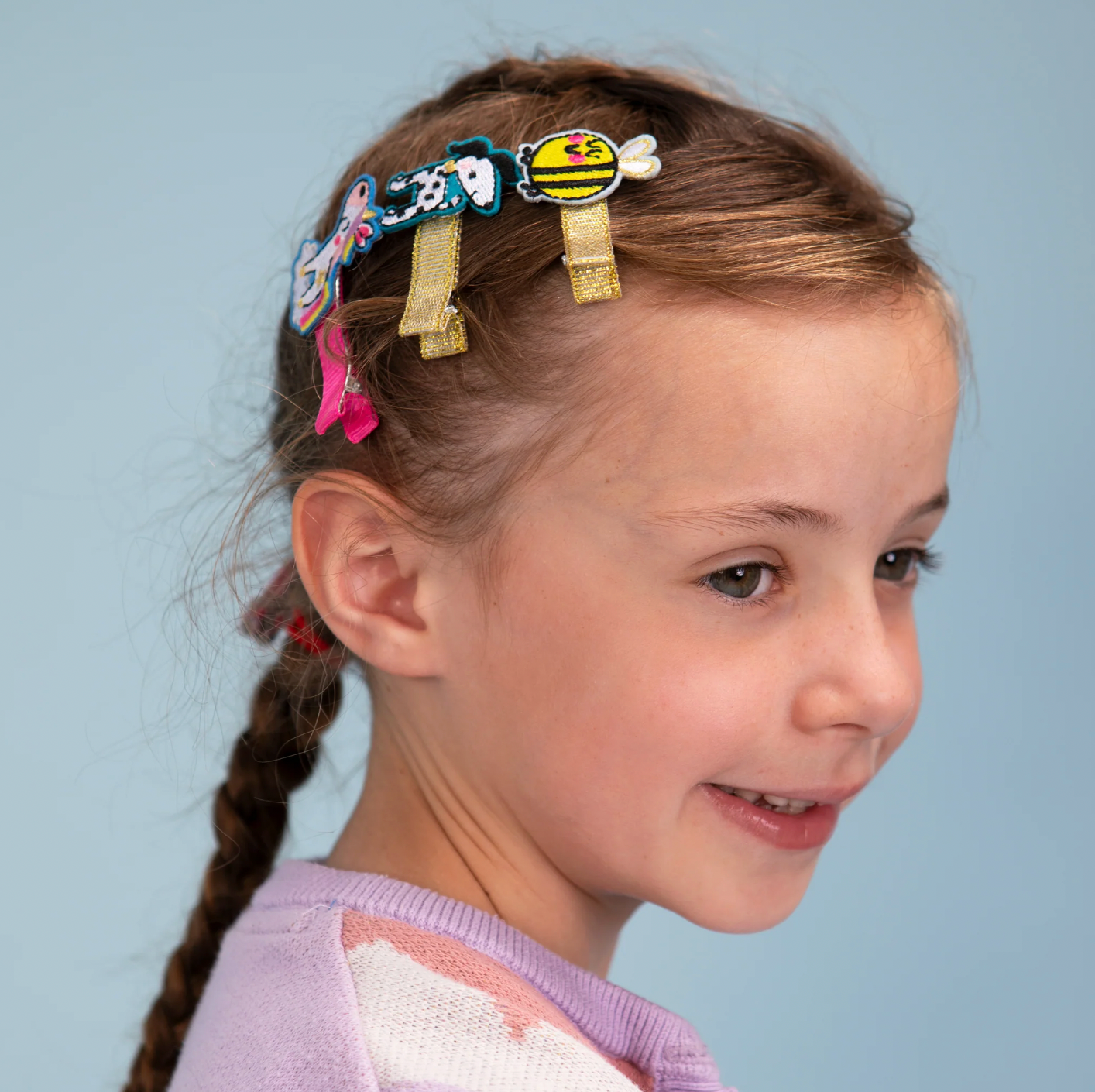 Young girl with colorful hair clips in her hair against a light blue background RACHEL ELLEN HAIR CLIPS - DOGS