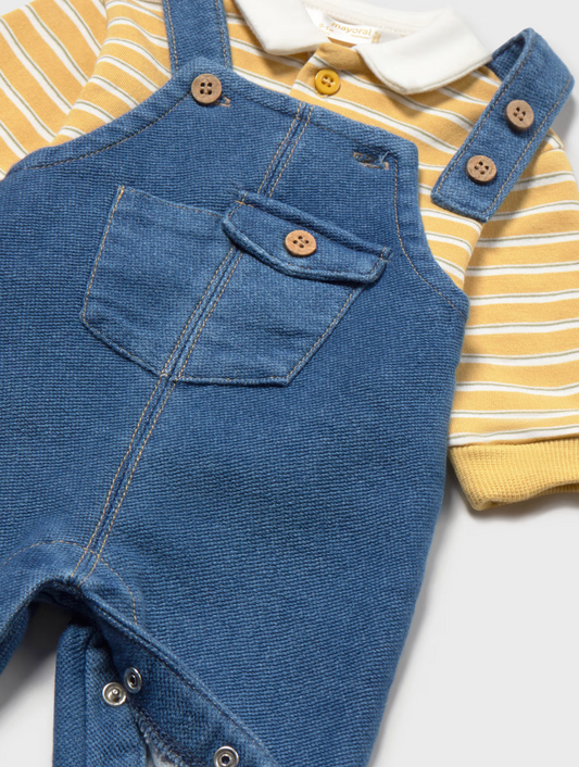 A baby clothing set featuring blue denim overall-style overalls layered over a yellow and white striped short-sleeve shirt with a white collar, shown on a light gray background.