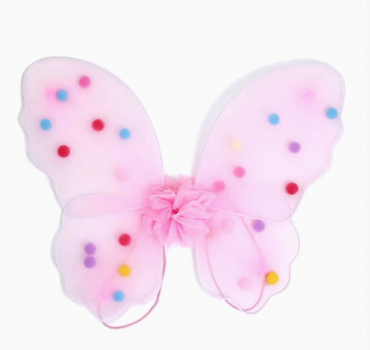 Child wearing lilac Molly & Rose Pom Pom Fairy Wings over a checked dress; matching elastic straps and colourful pompom details visible across the small net wings