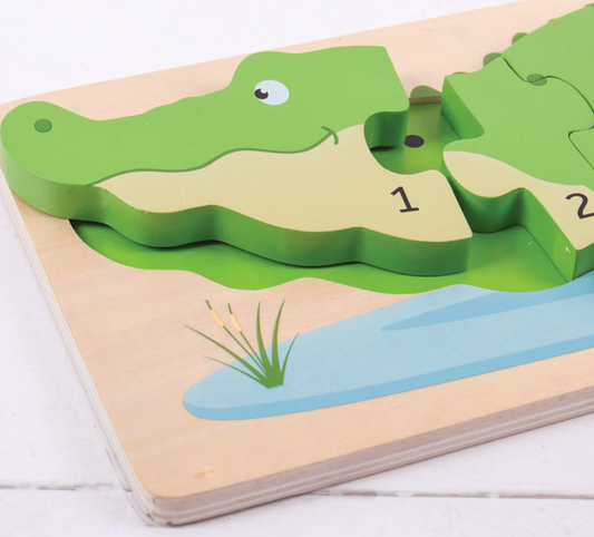 Wooden puzzle with green alligator pieces on a light wooden base. WOODEN CROCODILE NUMBER COUNTING 1-10 PUZZLE | BIGJIGS