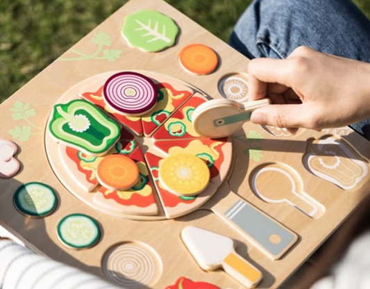 Child playing with a wooden toy pizza set outdoors. WOODEN SHAPE MATCHING PIZZA PUZZLE | CLASSIC WORLD