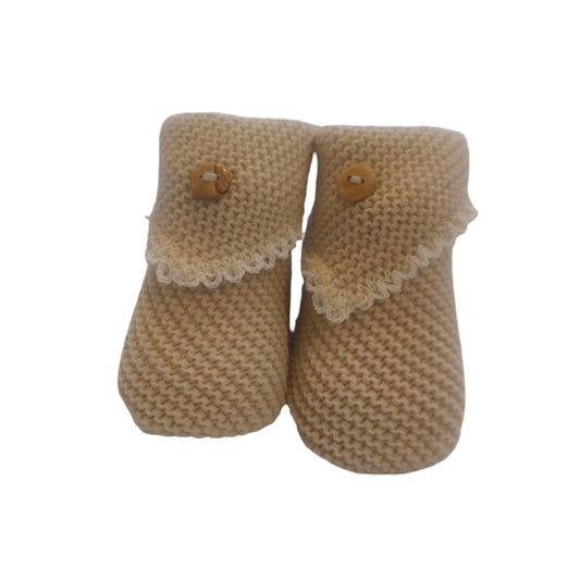 Pair of beige crochet-knit baby booties shown from the front on a white background; each bootie has a pale scalloped turn-down flap and a small wooden-look button