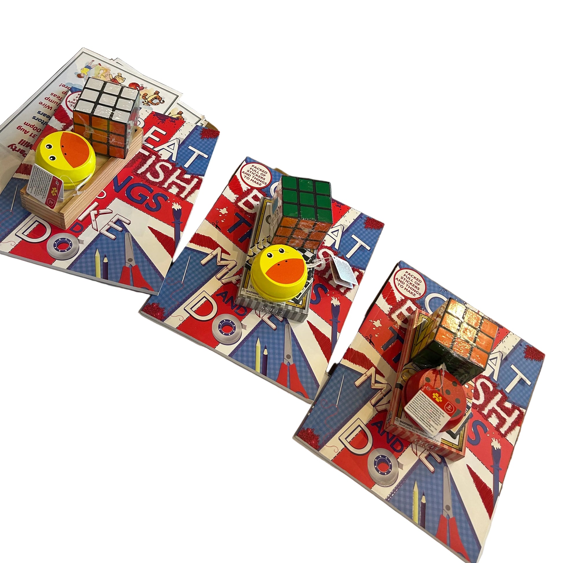 Three puzzle book sets with wooden Rubik's cubes displayed on a white tablecloth in a retail store. Each set features a red, white, and blue Union Jack themed book cover with the text 'EAT PISH DOG'.