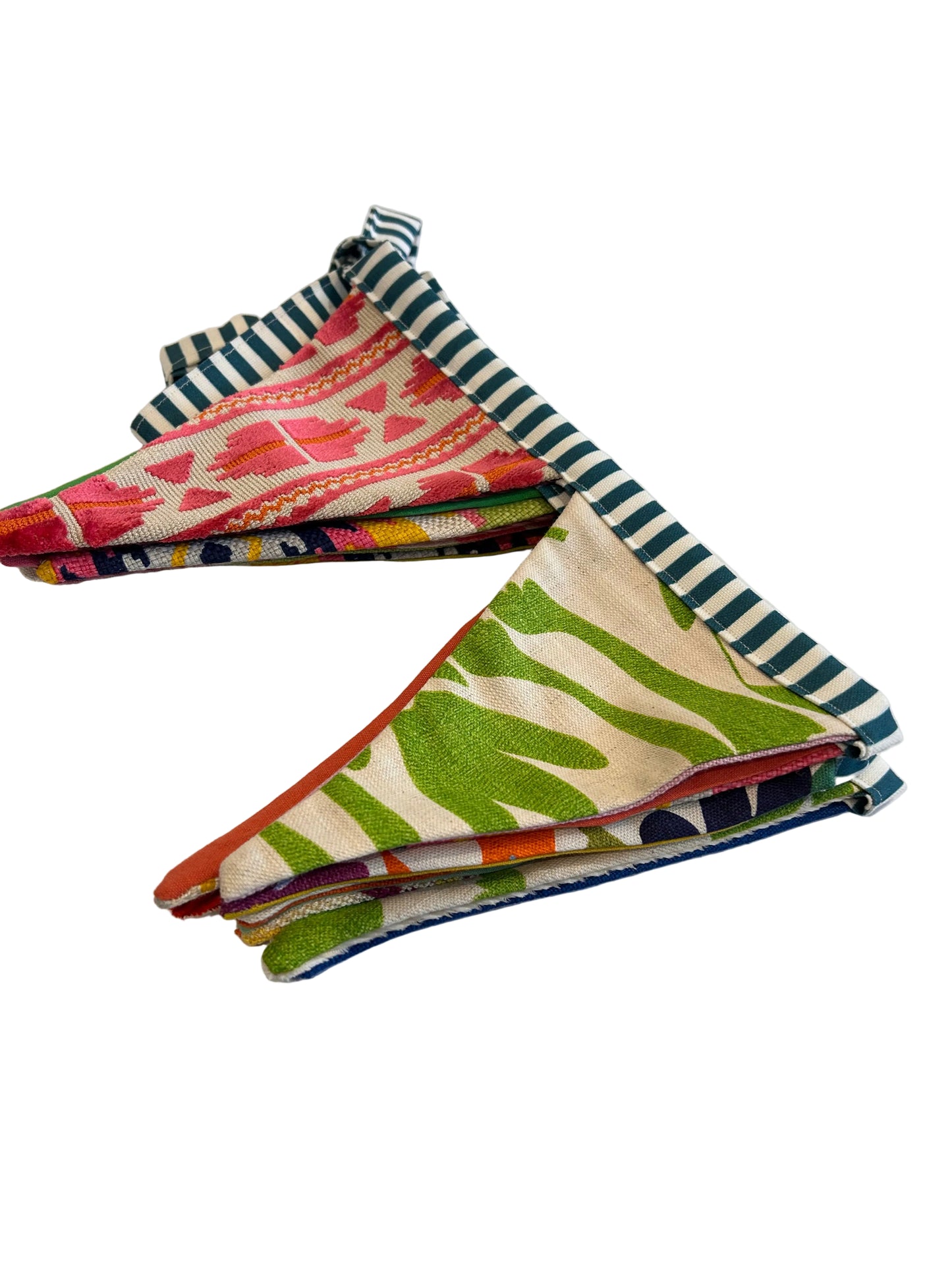 Colorful fabric strips hanging on a white surface with a wooden board and decorative items in the background.