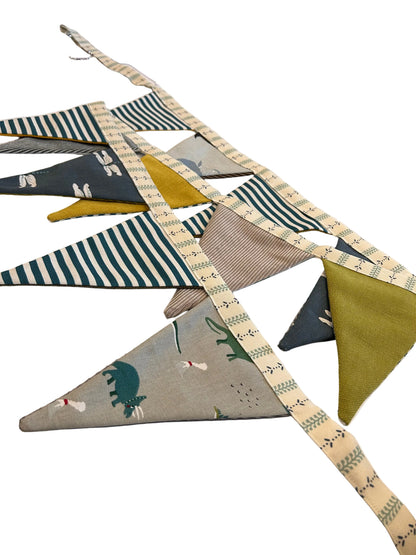 Fabric triangle banner with animal and nature patterns on a wooden surface.