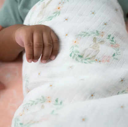 Close-up of a baby's hand holding a soft, textured blanket. ADEN + ANAIS COTTON BABY SWADDLE 4 PACK - BLUSHING BUNNIES