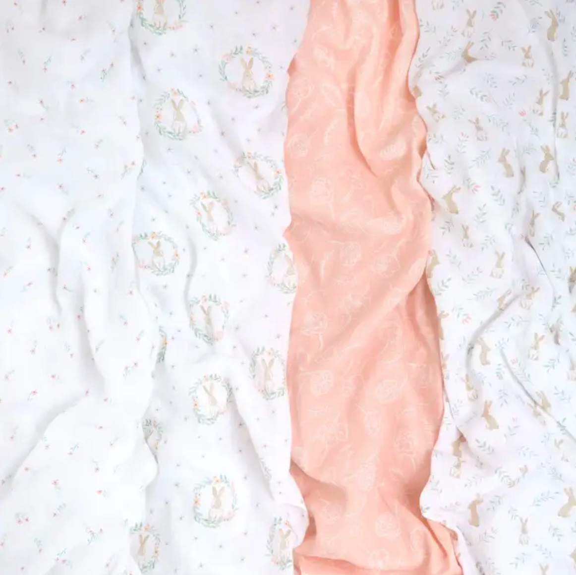 Close-up of a pink arm with a textured pattern against a white background ADEN + ANAIS COTTON BABY SWADDLE 4 PACK - BLUSHING BUNNIES