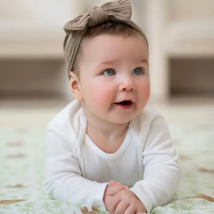 Baby wearing a white onesie and brown headband, lying on a soft surface. ADEN + ANAIS COTTON BABY SWADDLE 4 PACK - TANZANIA