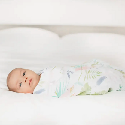 Baby swaddled in a floral blanket. ADEN + ANAIS COTTON BABY SWADDLE 4 PACK - TROPICALIA