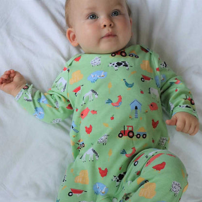 Baby wearing a green pajama with animal prints. BABY COTTON FARMYARD PRINT SLEEPSUIT WITH FEET | POWELL CRAFT