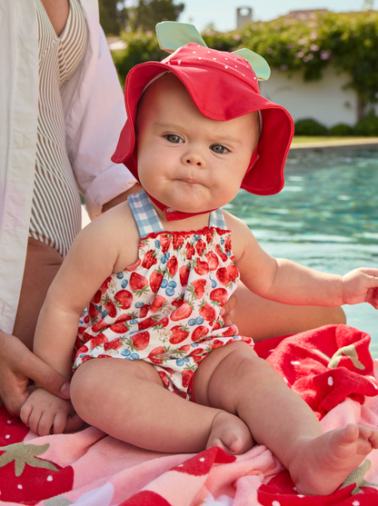 Baby in strawberry-themed swimsuit and hat sitting by a pool. BABY GIRLS STRAWBERRY SWIM BEACH SET - HAT, TOP AND KNICKERS | MAYORAL