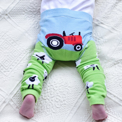 A pair of green leggings with a farm-themed design, including a red tractor on the knee area and a depiction of white sheep on the calf area, paired with a blue waistband. BABY TRACTOR & SHEEP LEGGINGS - 3 SIZES | POWELL CRAFT