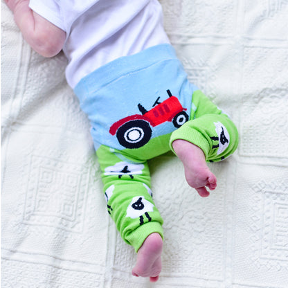 Baby legs in colorful FARM themed leggings on a white textured blanket. BABY TRACTOR & SHEEP LEGGINGS - 3 SIZES | POWELL CRAFT