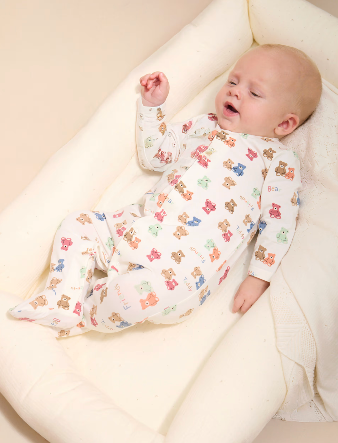 Baby wearing a white onesie with colorful bear patterns. BABY UNISEX SLEEPSUIT - RAINBOW TEDDY PATTERN | MAYORAL
