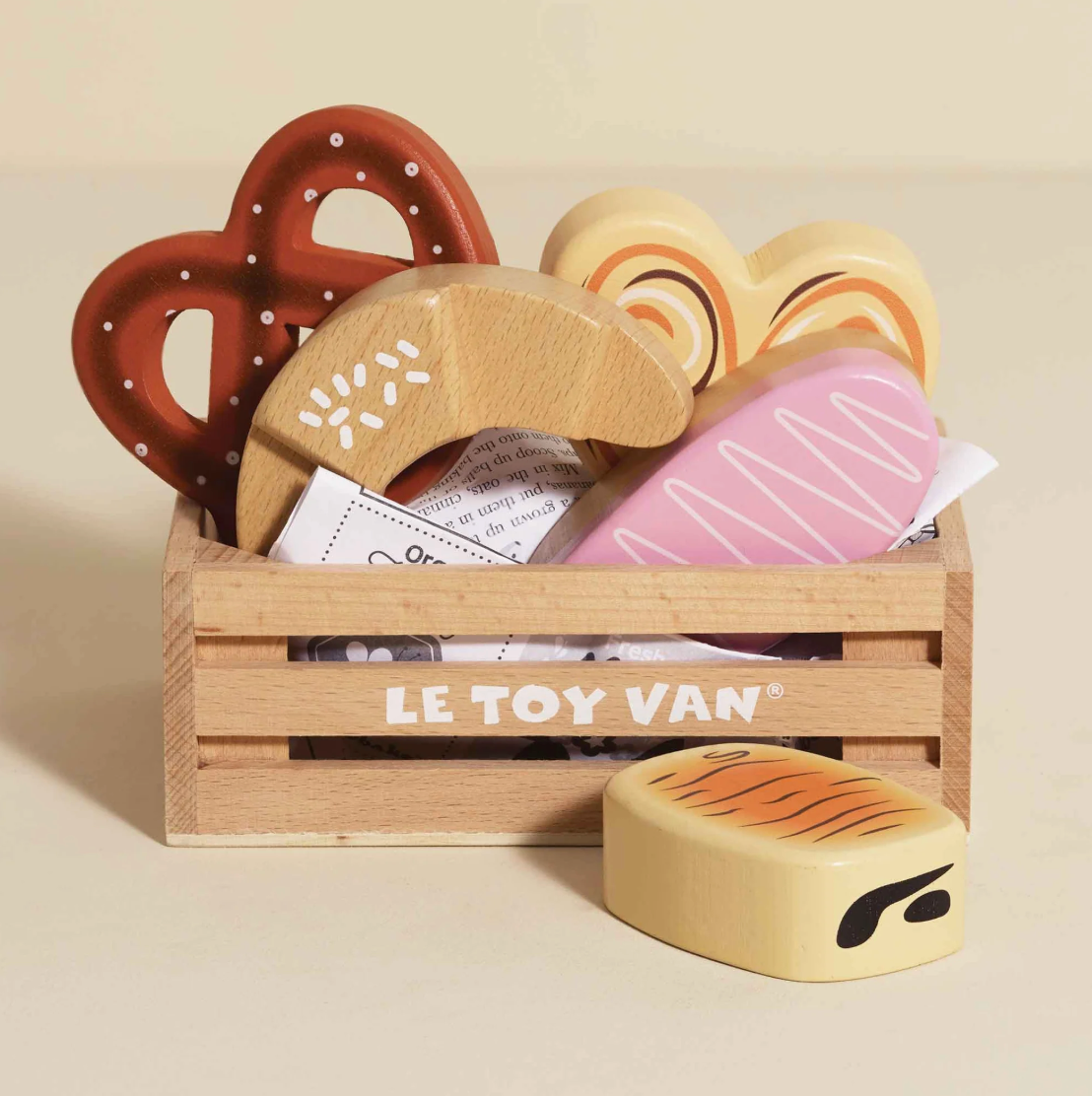Set of wooden toy food items in a crate with 'LE TOY VAN' branding on a beige background. BAKERY & PATISSERIE MARKET CRATE WOODEN TOY | LE TOY VAN