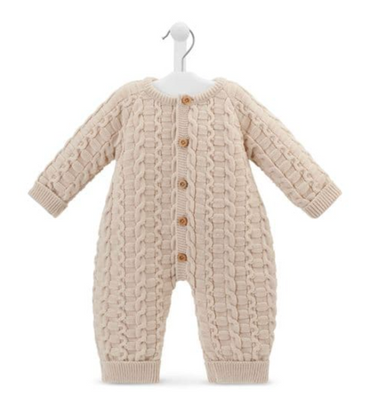 Dandelion basket weave knitted baby onesie in warm oatmeal taupe on a white hanger against a white background; full front view of a footless all-in-one with long sleeves and long legs; three-dimensional knit combining interlocking basket weave oval loop panels on the body and sleeves with twisted rope cable columns running vertically down the centre front and sides; five round gold-toned buttons down the centre front placket; round neckline with narrow ribbed neckband; ribbed cuffs at sleeve ends andbuttons