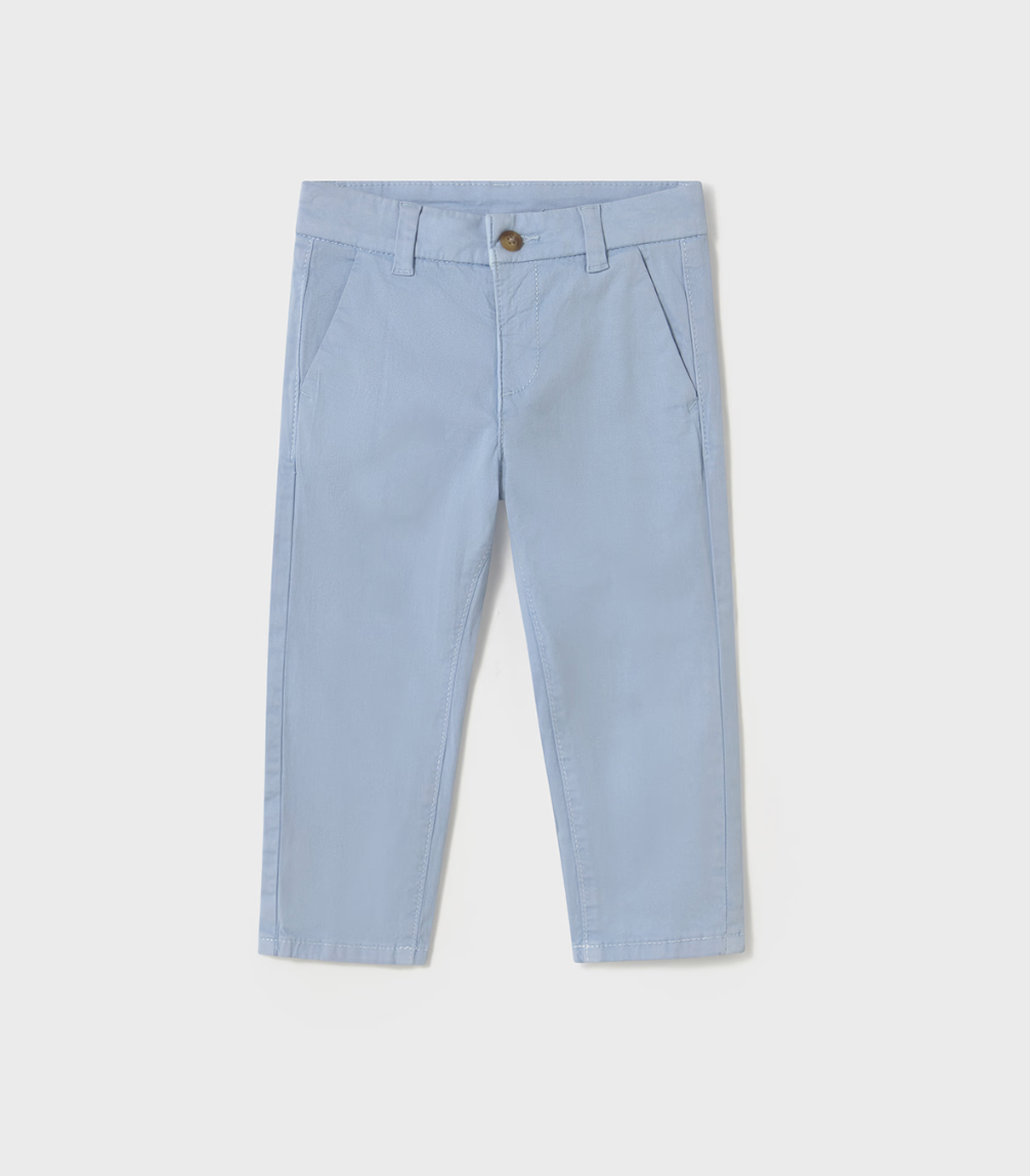 Mayoral Boys Basic Baby Blue Chino Trousers — front ghost flat-lay on light grey background; powder/pale blue cotton-elastane chino-style trousers; flat front with a pressed centre crease on each leg; concealed zip fly with a single small round antique/brass-tone metal button at the waistband clearly visible; belt loops at the waistband; two angled diagonal slash pockets at the front; plain straight-cut leg tapering slightly to a plain hemline at the ankle; light grey background; demonstrates the full front