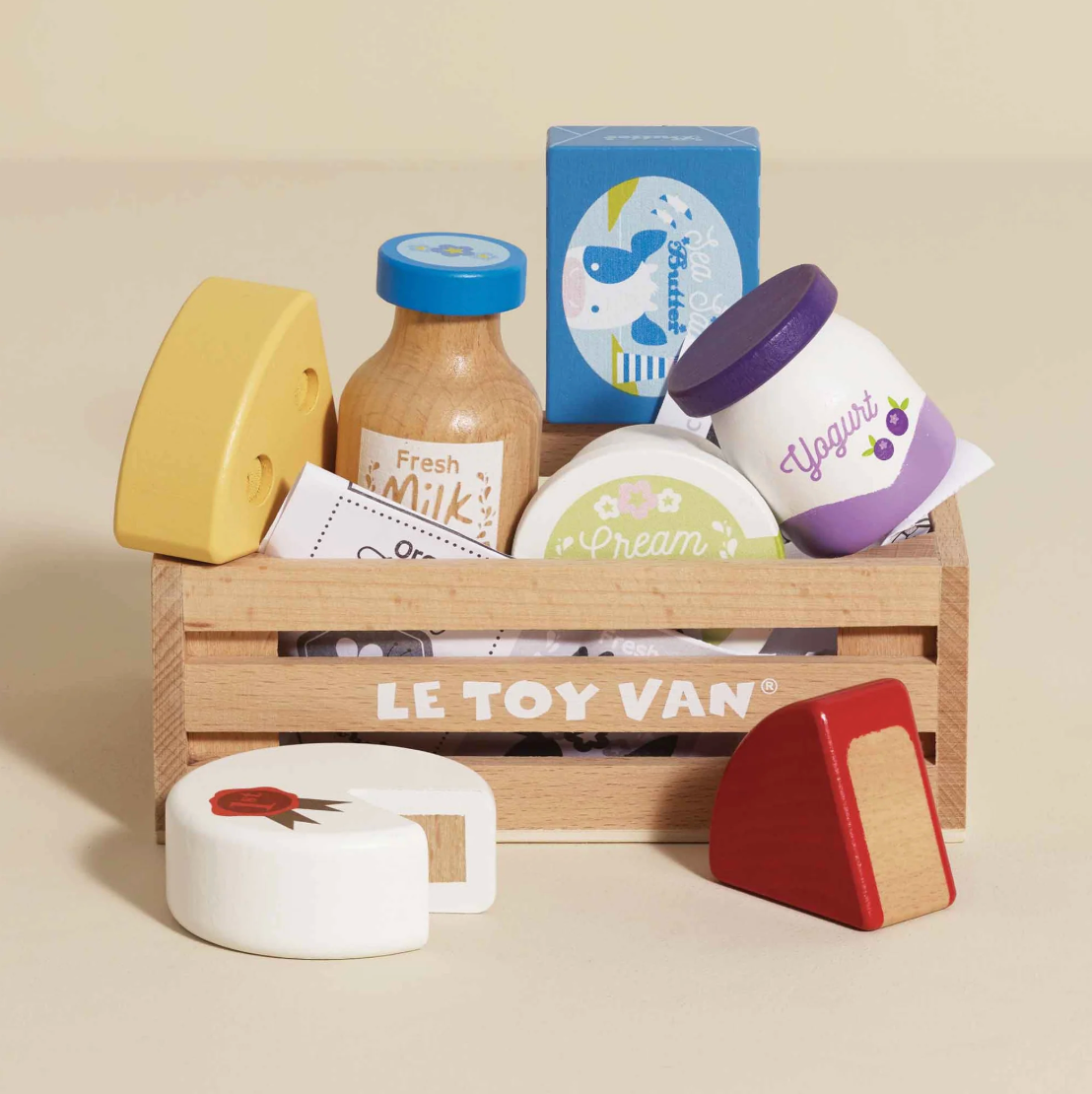 Le Toy Van toy food set with wooden crate and colorful toy food items on a beige background. CHEESE & DAIRY WOODEN TOY MARKET CRATE | LE TOY VAN