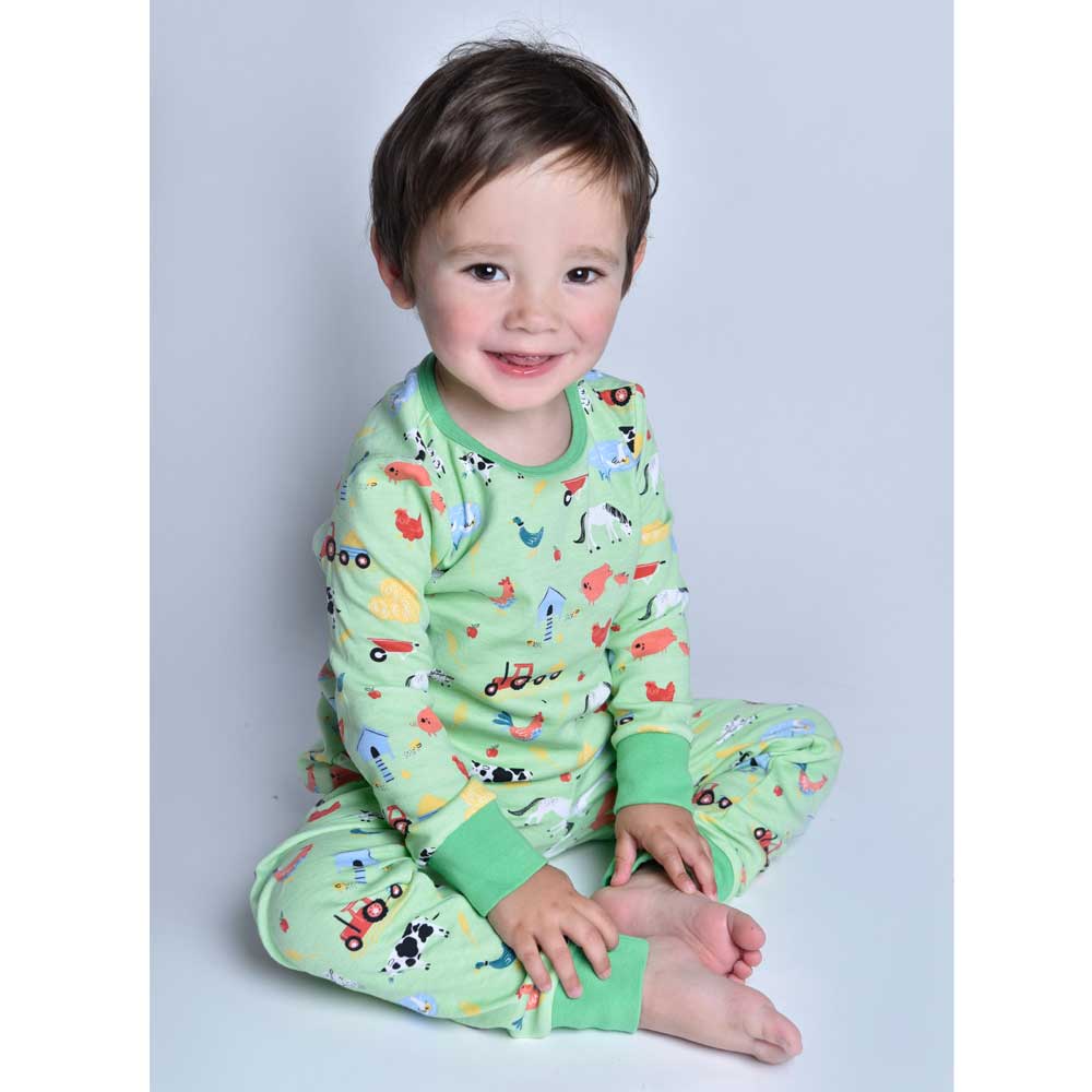 Child wearing green pajamas with farm animal prints on a plain background. CHILDREN'S COSY FARMYARD COTTON PYJAMAS - 3 SIZES | POWELL CRAFT