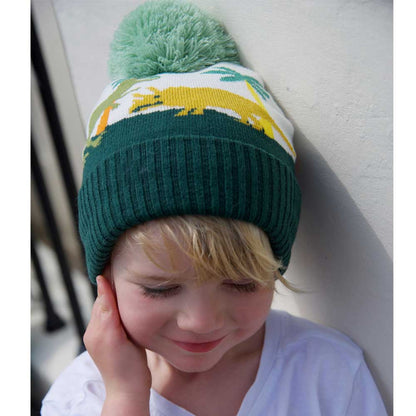 Child wearing a green knit hat with dinosaur design and pom-pom. CHILDREN'S DINOSAUR KNITTED HAT WITH POM-POM | POWELL CRAFT