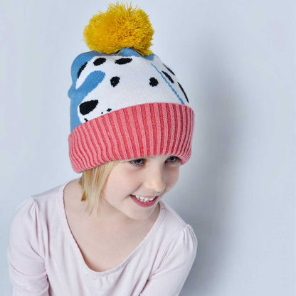 Child wearing a colorful knit hat with a yellow pom-pom. CHILDREN'S DOG KNITTED HAT WITH POM-POM | POWELL CRAFT