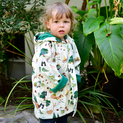 Child wearing a patterned raincoat standing among plants. CHILDREN'S GREAT OUTDOORS RAINCOAT - 3 SIZES | POWELL CRAFT 