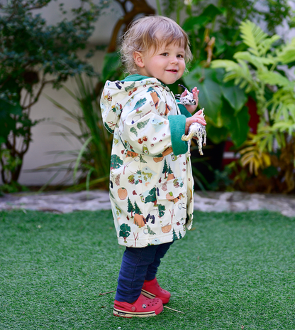 Child wearing a patterned coat standing on grass with plants in the background. CHILDREN'S GREAT OUTDOORS RAINCOAT - 3 SIZES | POWELL CRAFT