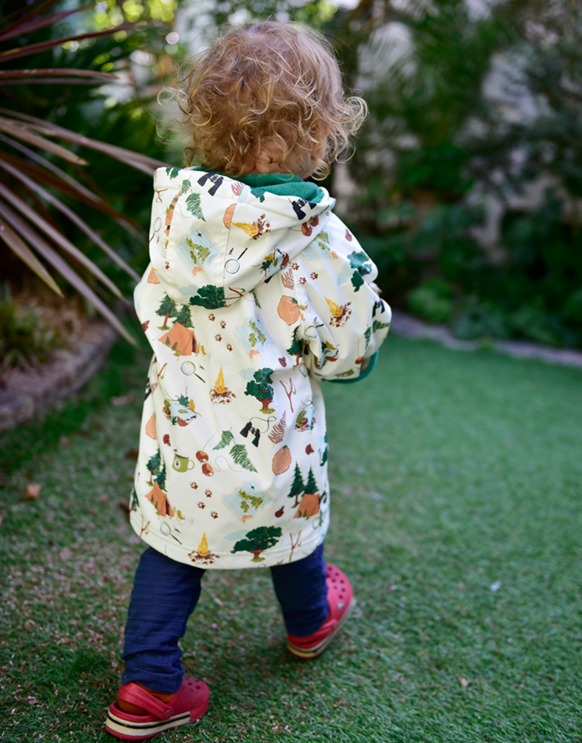 Child wearing a patterned coat walking outdoors on grass. CHILDREN'S GREAT OUTDOORS RAINCOAT - 3 SIZES | POWELL CRAFT