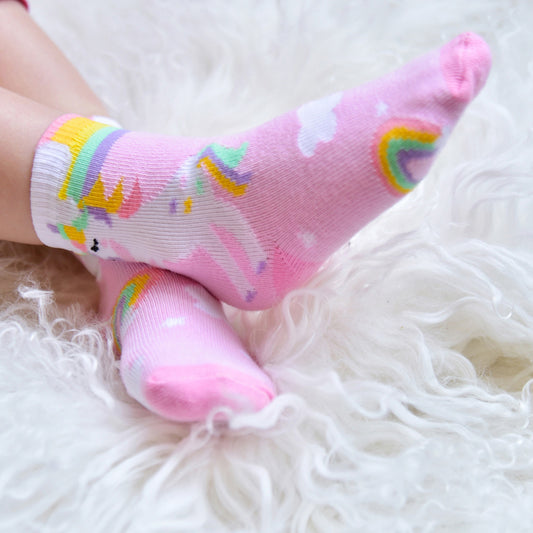 A pair of pink unicorn-themed socks with rainbow stripes and character decorations. CHILDREN'S PINK UNICORN & RAINBOW SOCKS - 3 SIZES | POWELL CRAFT