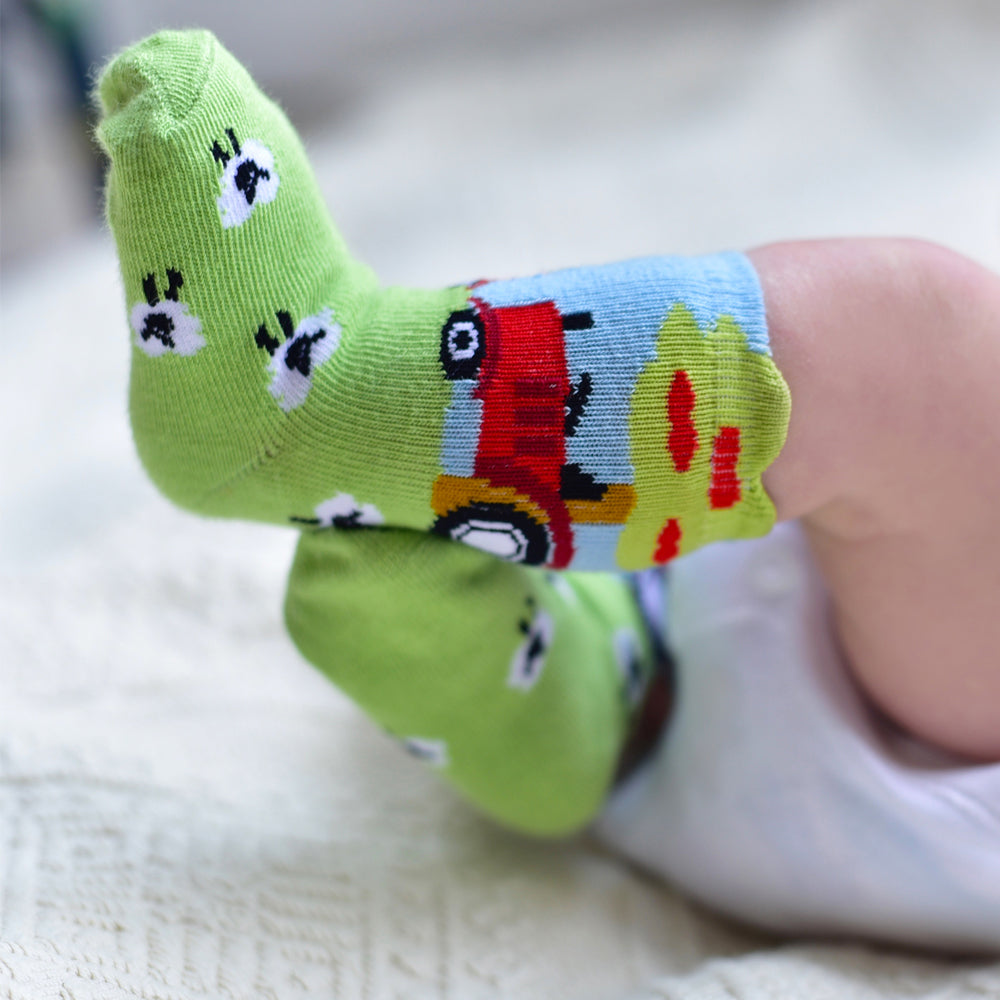 Colorful children's socks with cartoon designs on a baby's foot. CHILDREN'S TRACTOR & SHEEP SOCKS - 4 SIZES | POWELL CRAFT
