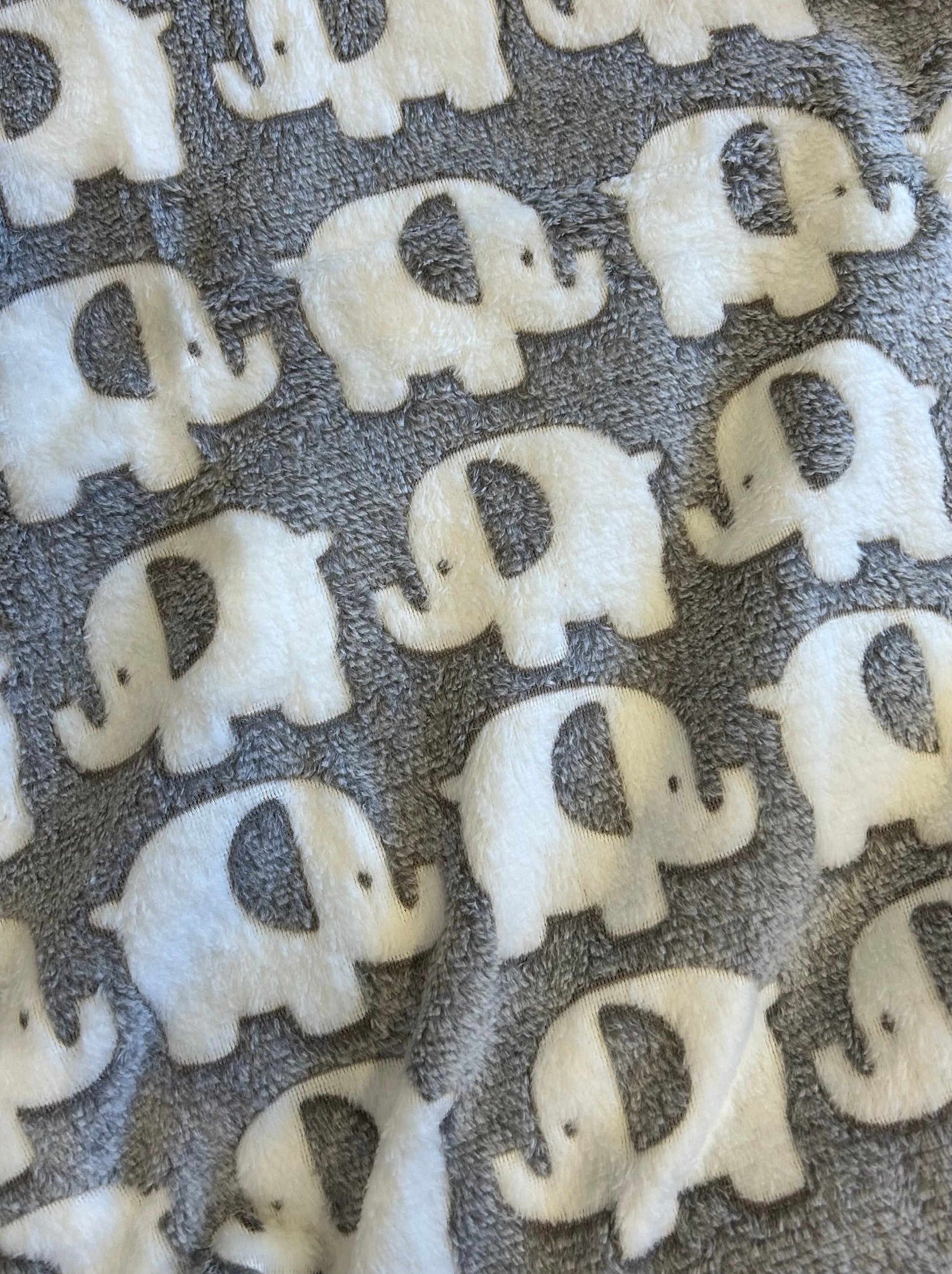 Pattern of white elephant shapes on a textured gray background. COSY BABY WRAP | GREY ELEPHANT