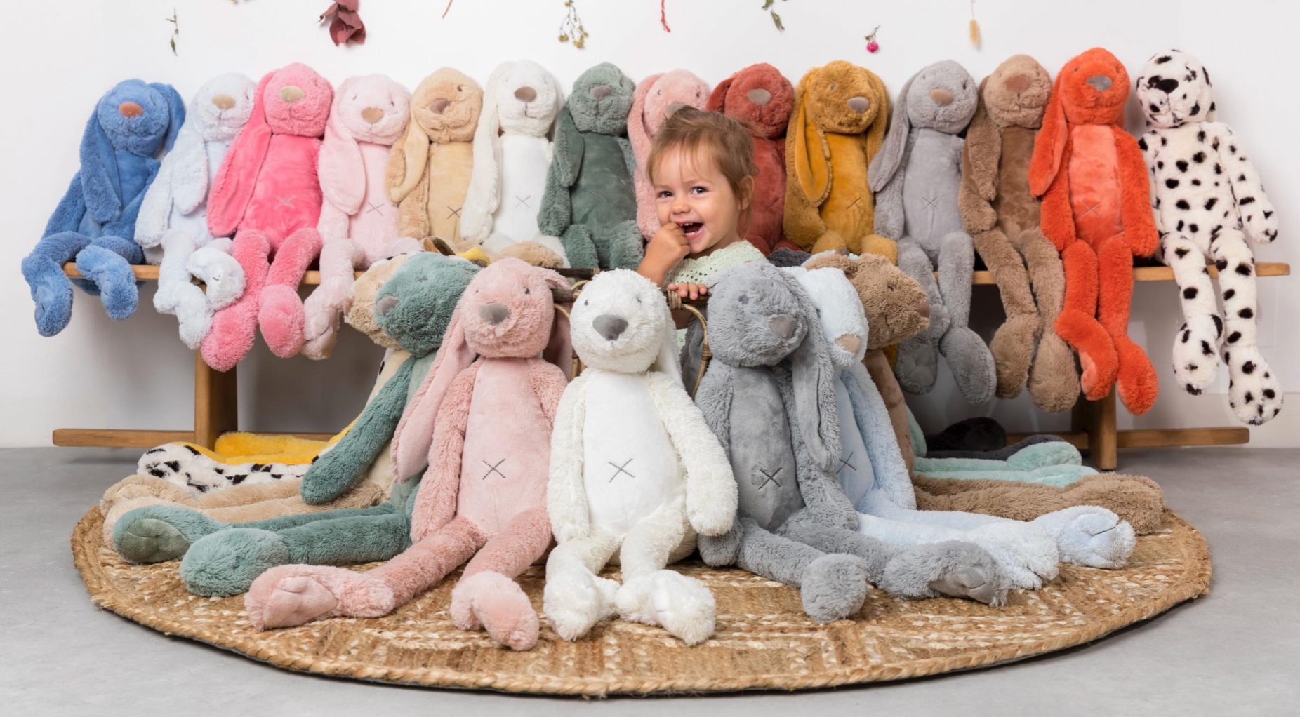Child surrounded by colorful stuffed animals on a wooden shelf. CUDDLY PLUSH RICHIE RABBIT BEIGE - 3 SIZES | HAPPY HORSE