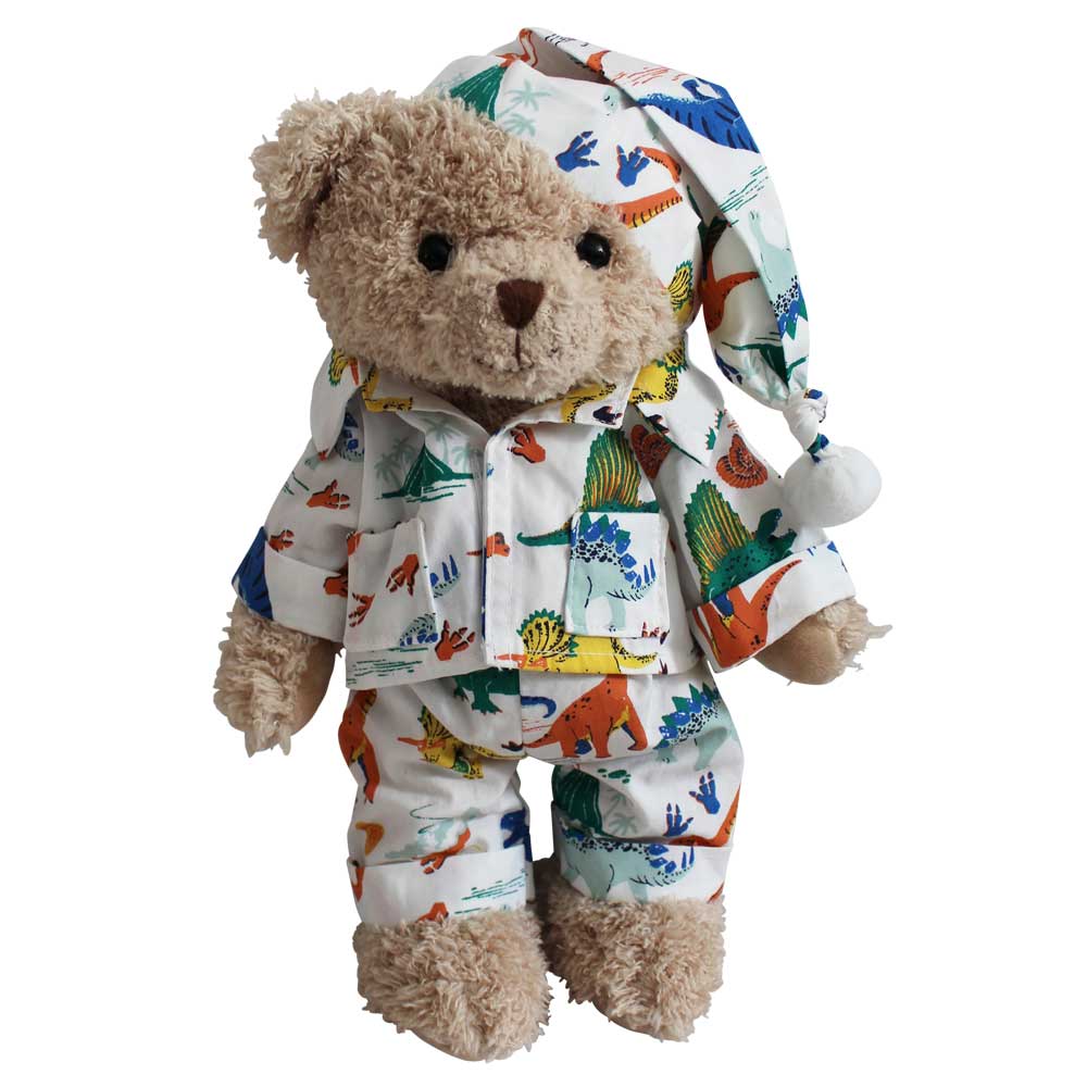 A teddy bear wearing a colorful dinosaur print pyjama set with a matching sewn-on nightcap.