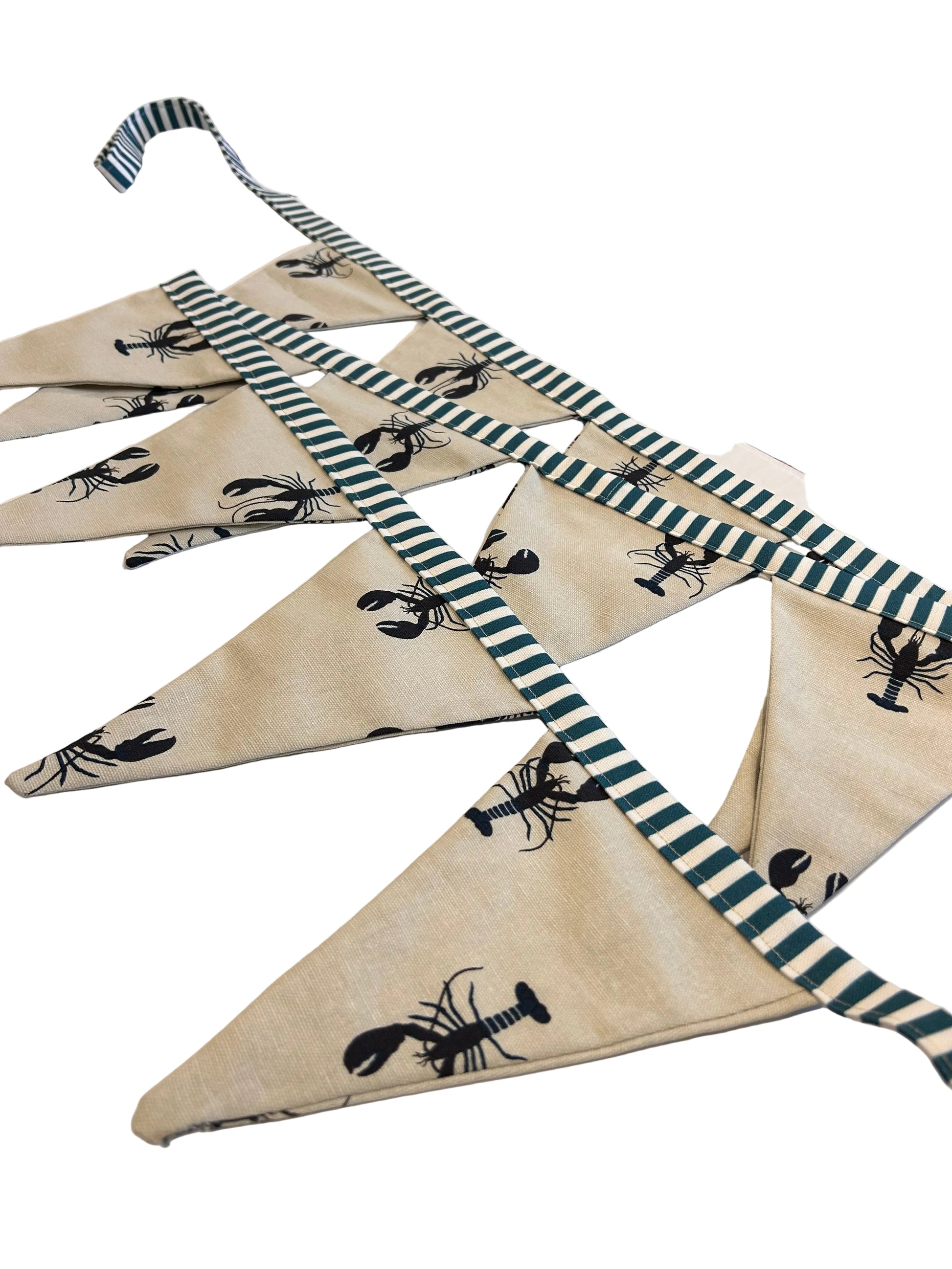 Decorative fabric with black lobster pattern and striped border on a wooden surface.