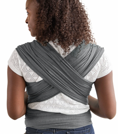 Person wearing a gray baby carrier wrap on a white background. ELEMENTS SOFT & ADJUSTABLE FEATHER KNIT BABY WRAP CARRIER - 2 COLOURS | MOBY