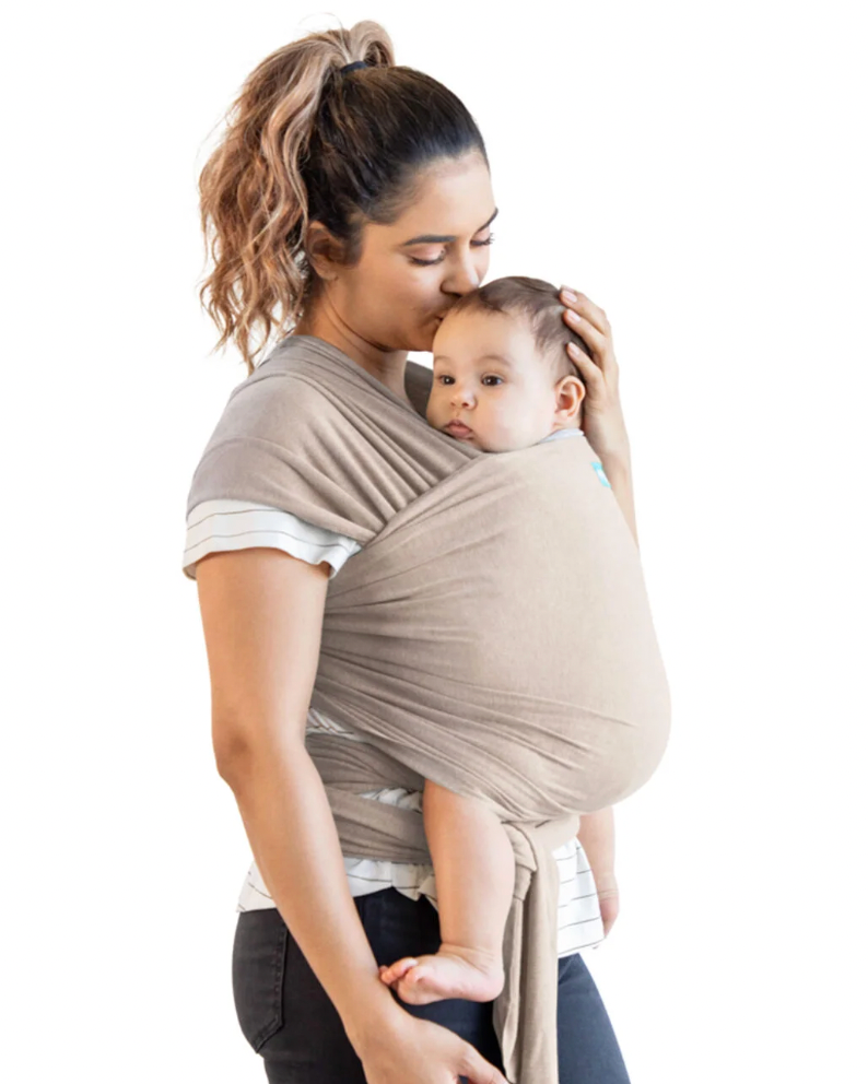 Woman holding a baby in a beige wrap carrier against a white background. ELEMENTS SOFT & ADJUSTABLE FEATHER KNIT BABY WRAP CARRIER - 2 COLOURS | MOBY