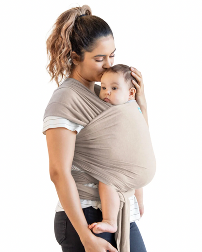Woman holding a baby in a beige wrap carrier against a white background. ELEMENTS SOFT & ADJUSTABLE FEATHER KNIT BABY WRAP CARRIER - 2 COLOURS | MOBY