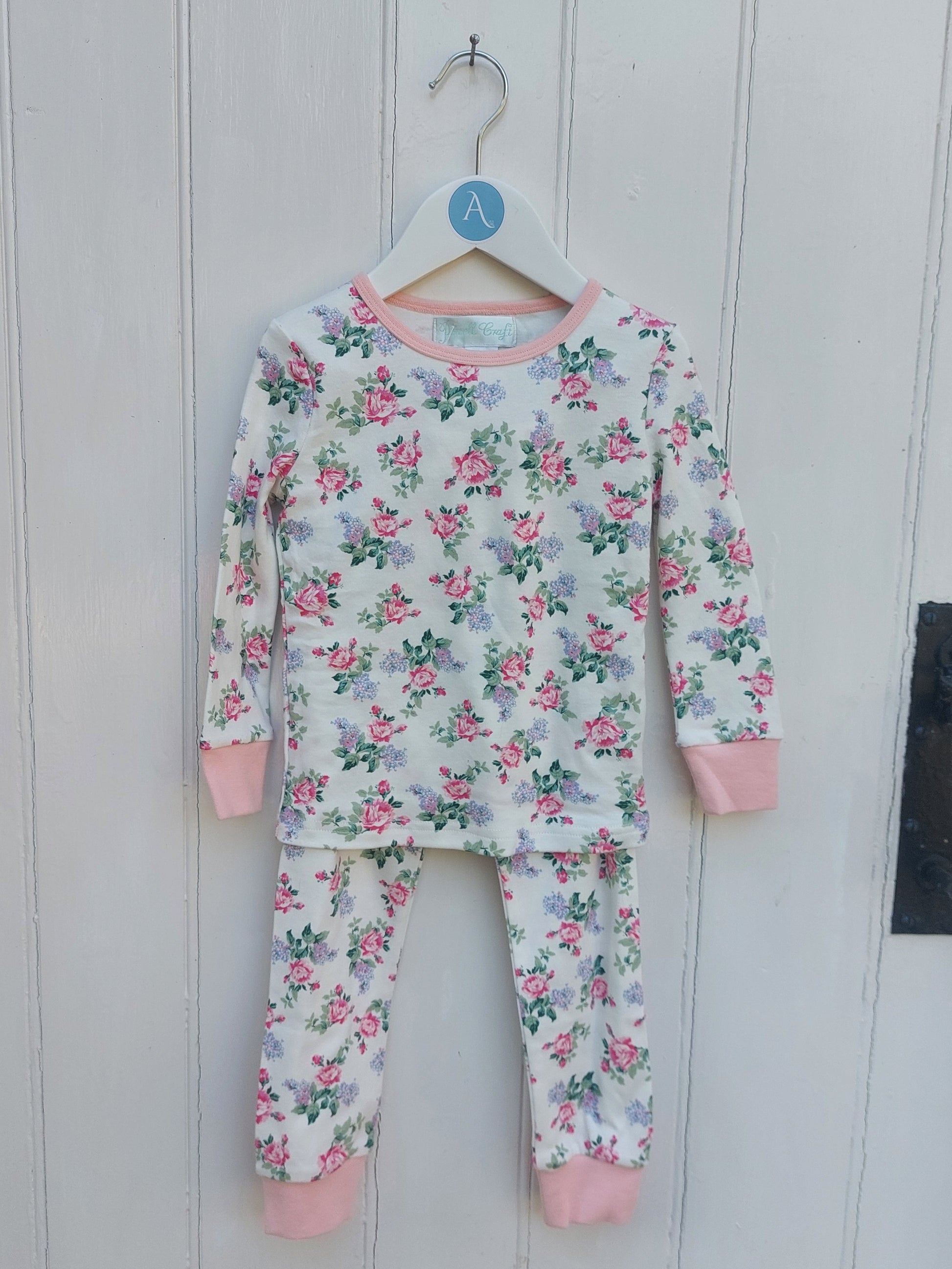 Floral pajama set with pink accents on a white wooden background. GIRL'S ENGLISH GARDEN FLOWER COTTON TOP & BOTTOM PYJAMAS - 3 SIZES | POWELL CRAFT