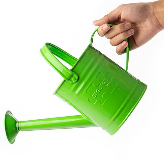 A green metal watering can with a fixed spout and two handles, being held by a hand. KIDS WATERING CAN - GREEN | BIGJIGS