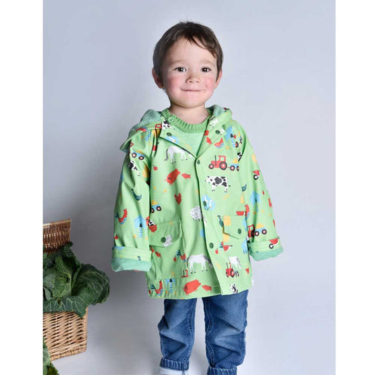 Child wearing a green raincoat with farm animal prints. KID'S FARMYARD LINED RAINCOAT - 4 SIZES | POWELL CRAFT