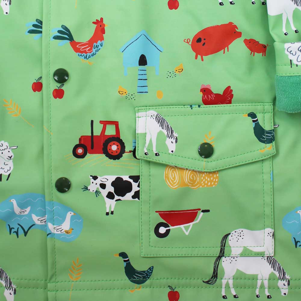 Green children's clothing with farm animal patterns on a close-up of the pocket. KID'S FARMYARD LINED RAINCOAT - 4 SIZES | POWELL CRAFT
