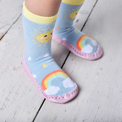 Children's socks with rainbow and sun designs on a wooden floor. KID'S SUNSHINE MOCCASIN NON-SLIP SLIPPER SOCKS - 4 SIZES | POWELL CRAFT