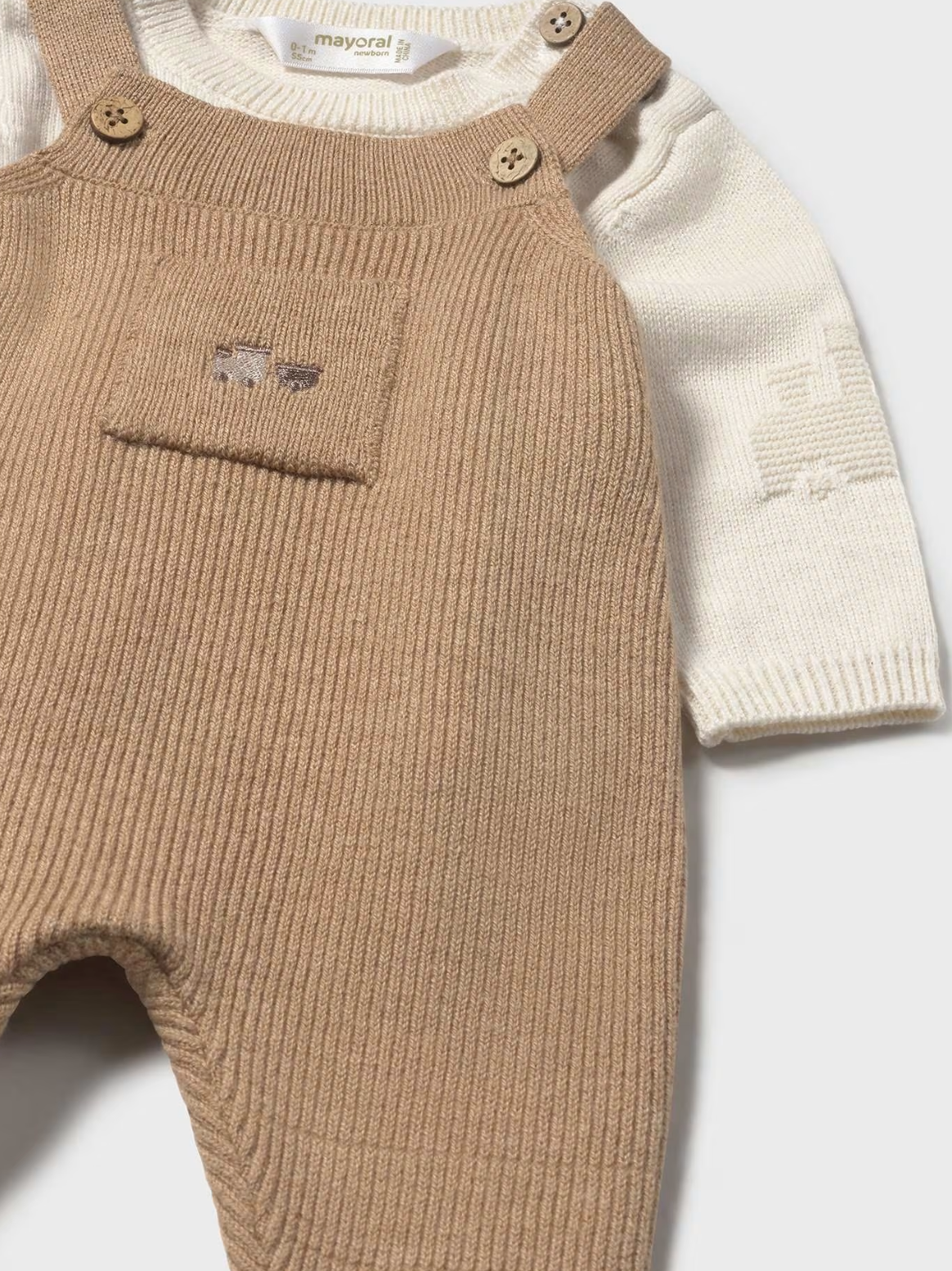 Mayoral baby 2-piece knit set in toffee — close-up of the upper front showing the toffee ribbed dungaree bib with two wooden buttons, small chest pocket with tiny embroidered bear motif, and the cream fine knit sweater with subtle textured sleeve pattern and Mayoral label at the neck